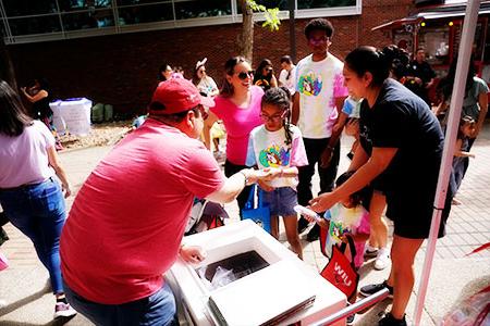 Alumnus handing food to child